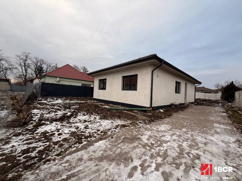 A family house in Veľký Grob, with a plot covered with snow and soil, without landscaping.