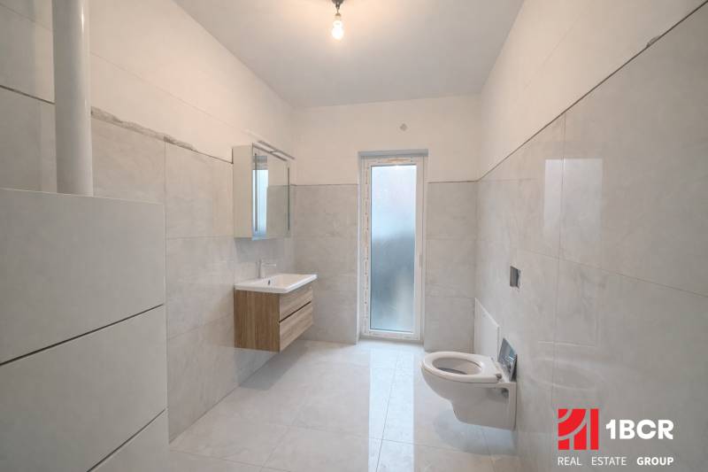 Bathroom in a family house with white tiles and a wall-mounted sink.