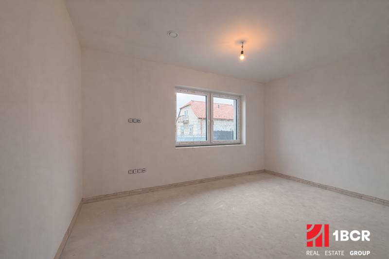A spacious room in a family house with a window overlooking another house.