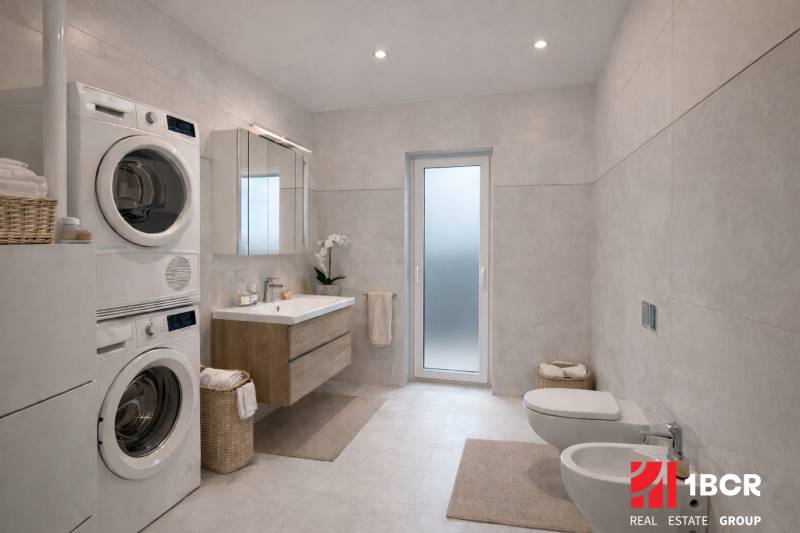 A bathroom in a family house with a shower, washing machine, and dryer with white tiles.