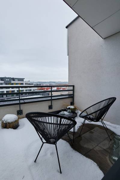 Snow-covered balcony with chairs and a view of Strojárenská Street in Košice, Old Town.