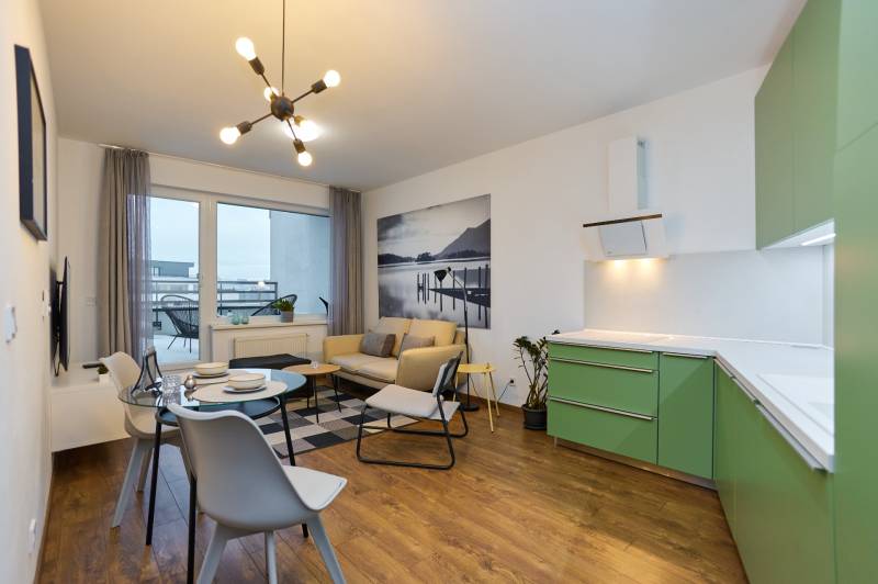 Living room with a kitchenette in a 2-room apartment, floor with wooden decor, green cabinets.