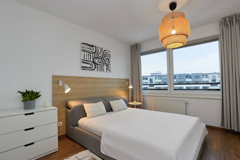 Bedroom in a two-room apartment with a bed, dresser, and floor with wood decor.