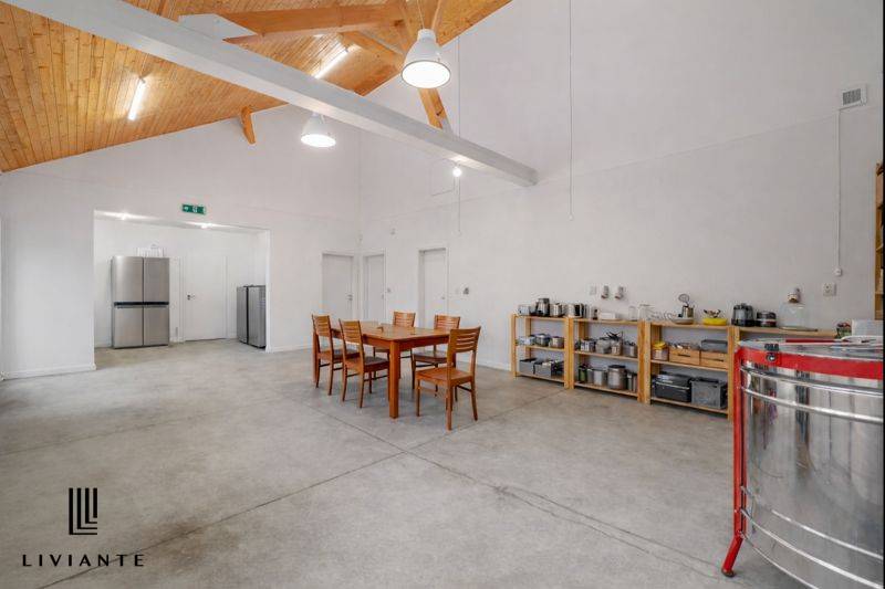 Interior of a building with a concrete floor, a table with chairs, and kitchen equipment.