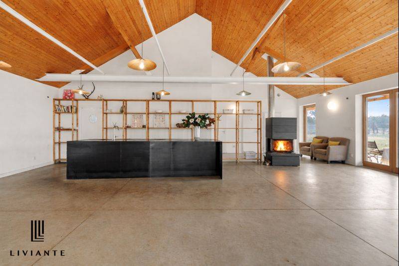 The interior of a building with a floor, minimalist furniture, a fireplace, and large windows.