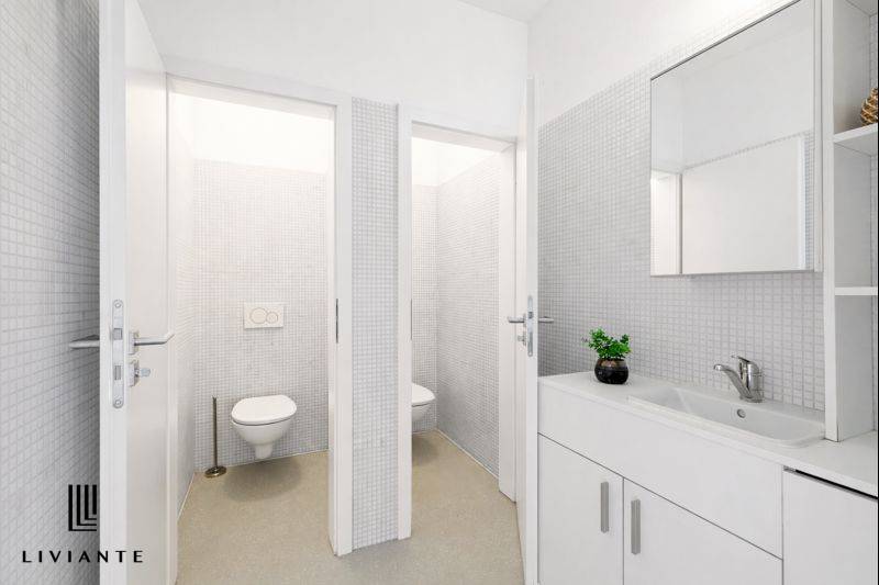 A bright bathroom with two toilets and a sink in the building.