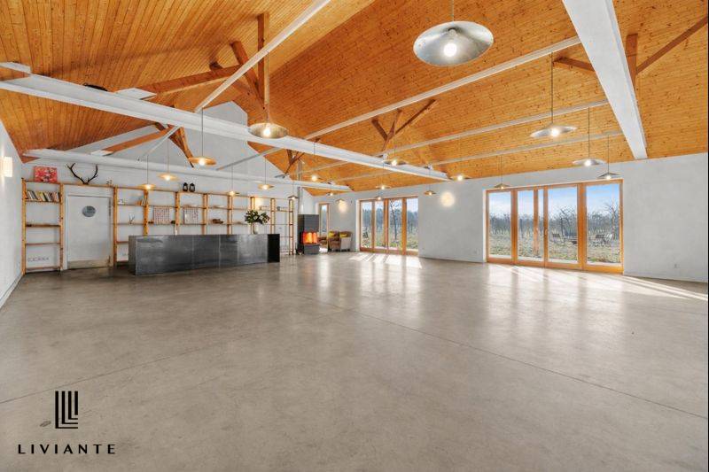 A spacious interior of a building with a high wooden ceiling and a concrete floor.