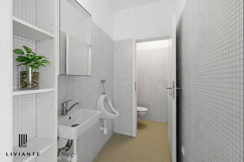 A restroom in a building with white tiles and an elegant sink.