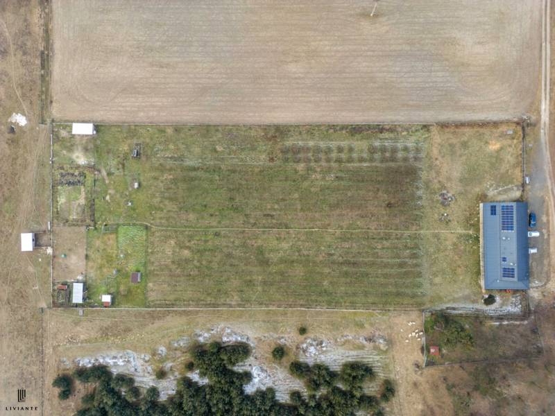 Aerial view of agricultural land with a building on the edge in the village of Láb.