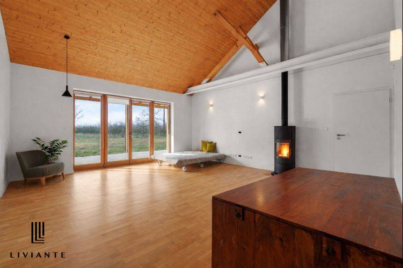 Interior of a building with a fireplace, large windows, and a wooden decor floor.
