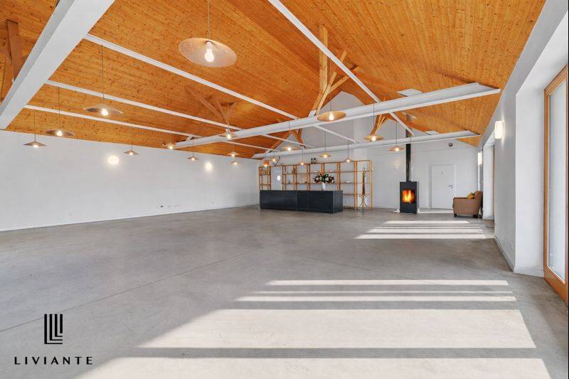 A space in a building with a wooden ceiling, large windows, and a reception desk.