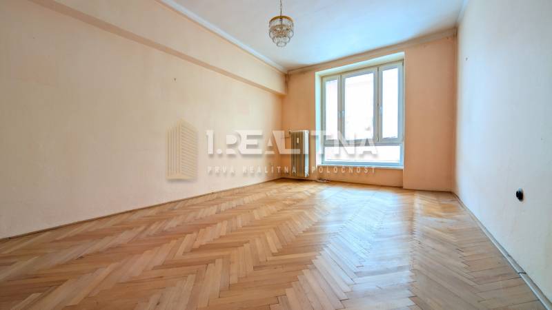 A bright room in a 2-room apartment with a wood-patterned floor and a large window.