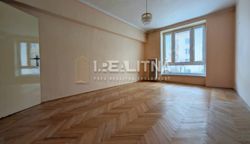 Spacious room in a 2-room apartment with wood-patterned flooring and a large window.
