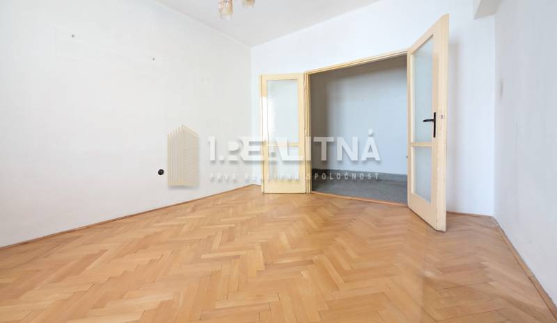 An empty room with white walls and a wooden decor floor in a two-room apartment.