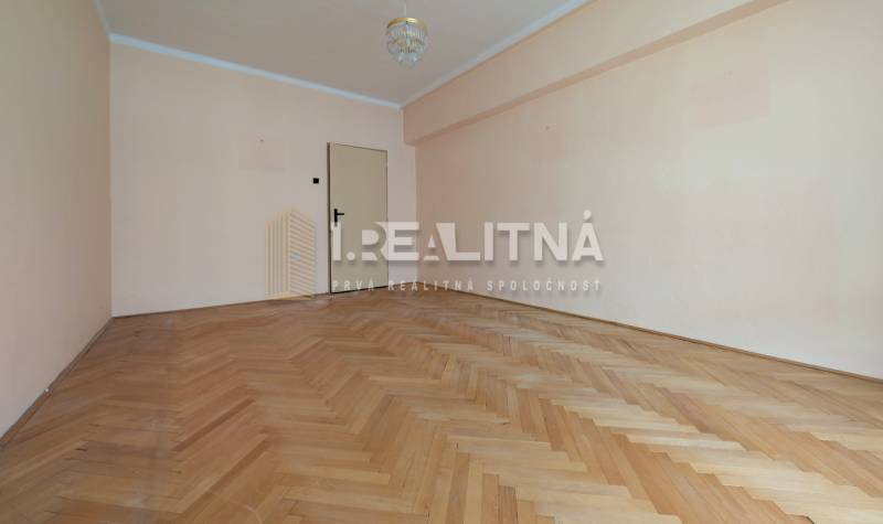 A spacious room with a wooden decor floor in a 2-room apartment.