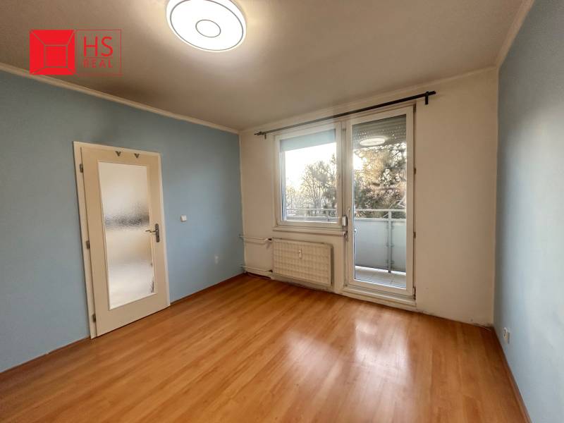 A room in a 3-room apartment with a wood-patterned floor and a balcony.