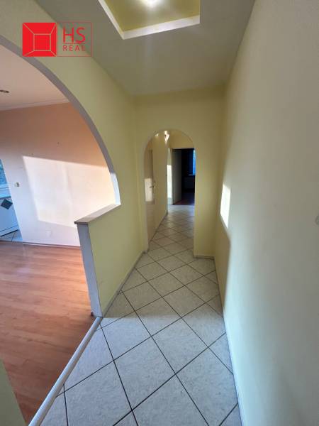 A hallway in a 3-room apartment with an arched entrance and tiles, leading to the rooms.