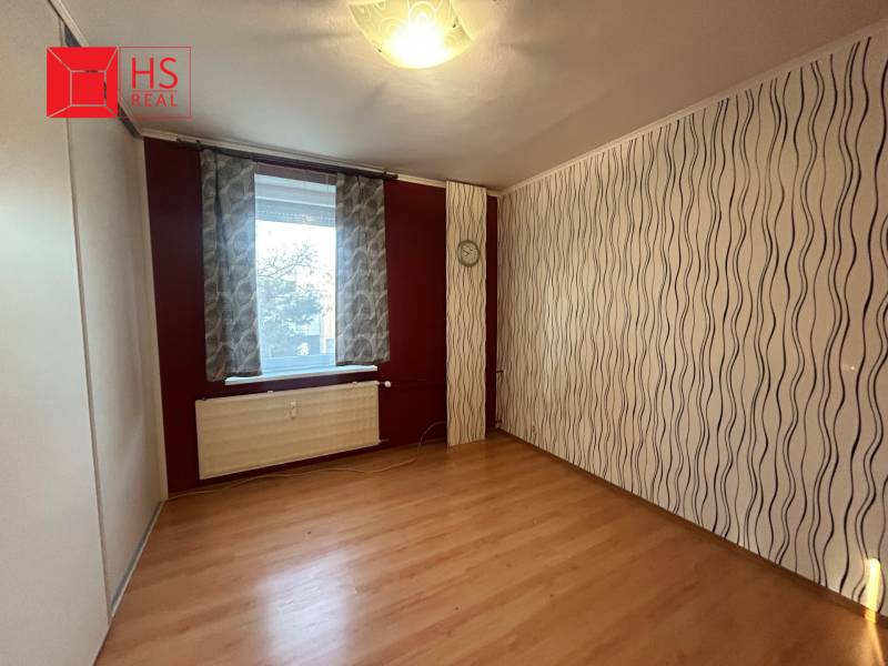 A room in a 3-room apartment with a wooden decor floor and wavy wallpaper.