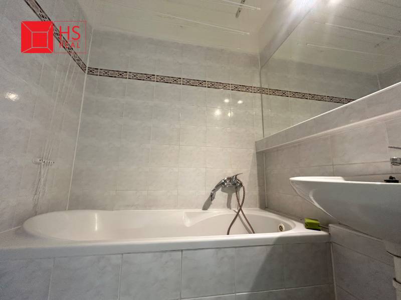The bathroom with a bathtub and a sink in the 3-room apartment has light tiles.