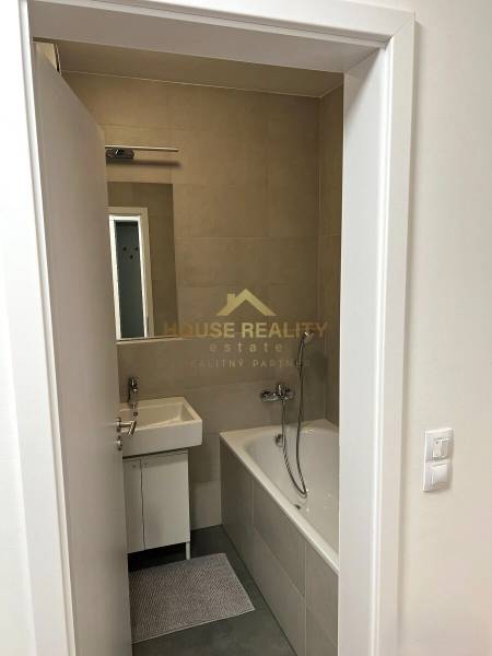 Bathroom in a 2-room apartment with a bathtub, sink, and tiles.