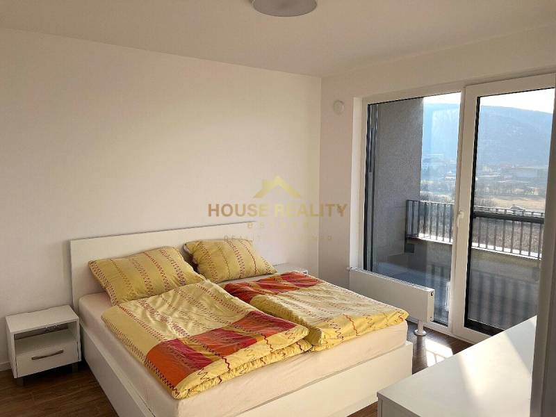 A bedroom in a 2-room apartment with light furniture and a wooden decor floor.