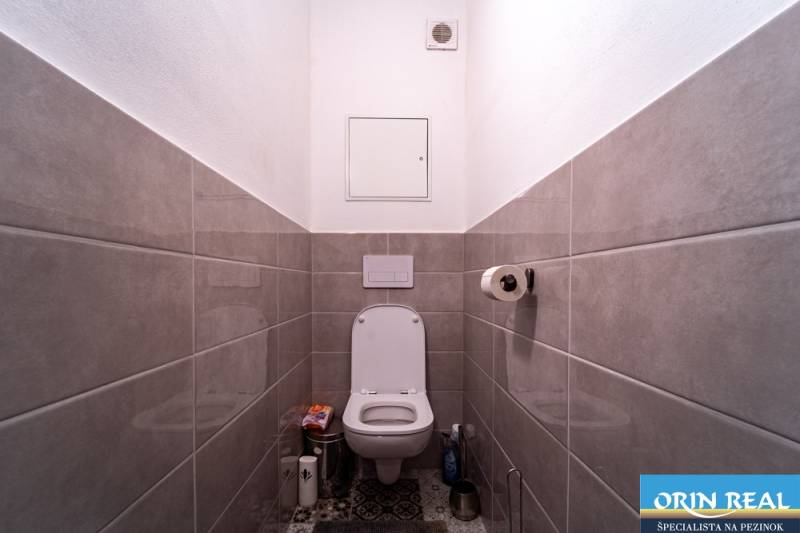 Bathroom with ceramic tiles and a toilet in a 2-room apartment.