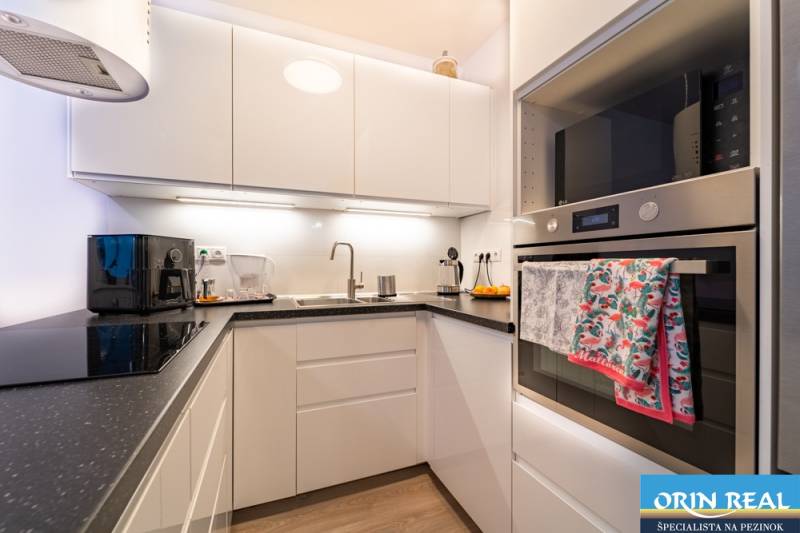 Compact kitchen with a black countertop in a 2-room apartment, floor with wood decor.