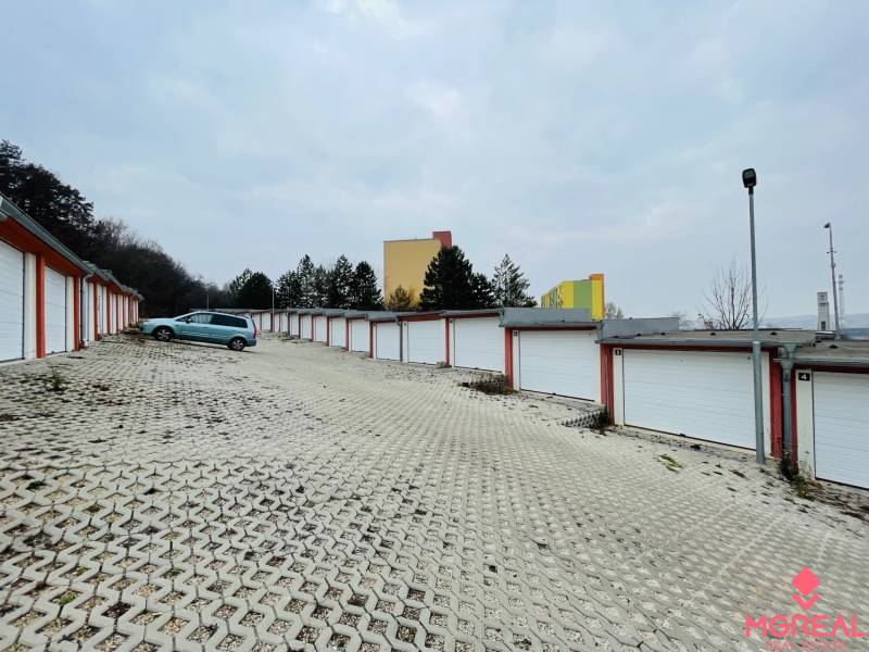 Garages on Rázdolie Street in Malé Uherce with a gravel driveway and a parked car.
