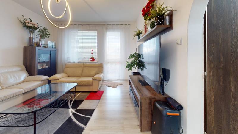 Living room in a 3-room apartment with cream furniture and wooden decor flooring.