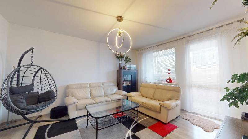 Living room in a 3-room apartment with a sofa, an armchair, and a floor with a wooden decor.