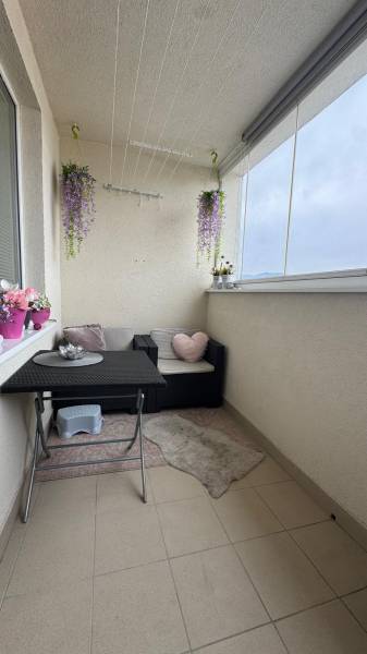 A furnished balcony with seating and hanging flowers in a 3-room apartment.