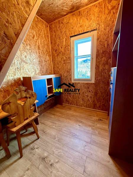 A room in a cabin with OSB boards and a wood-decor floor.