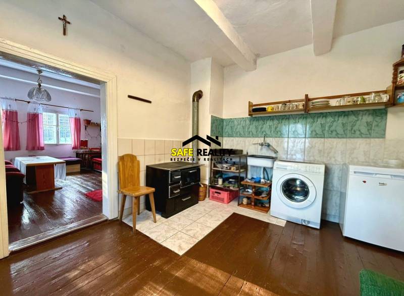 A cottage with a kitchen and living room, wooden decor flooring, white furniture, and an oven.