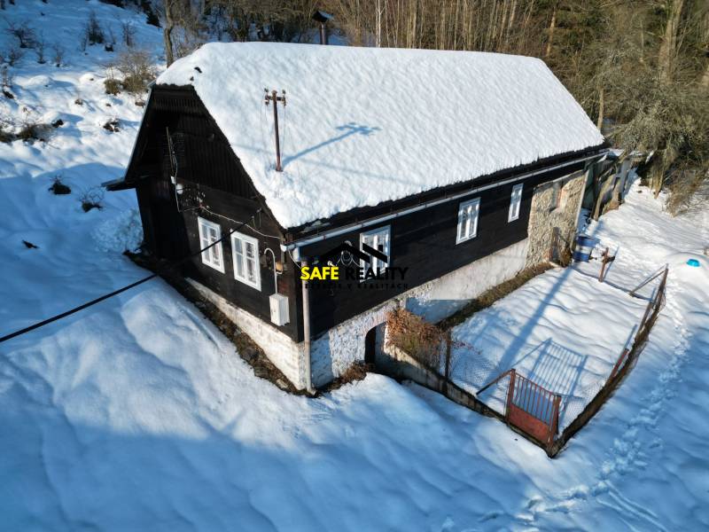 A snow-covered cottage in Veľké Rovné surrounded by a winter landscape and trees.
