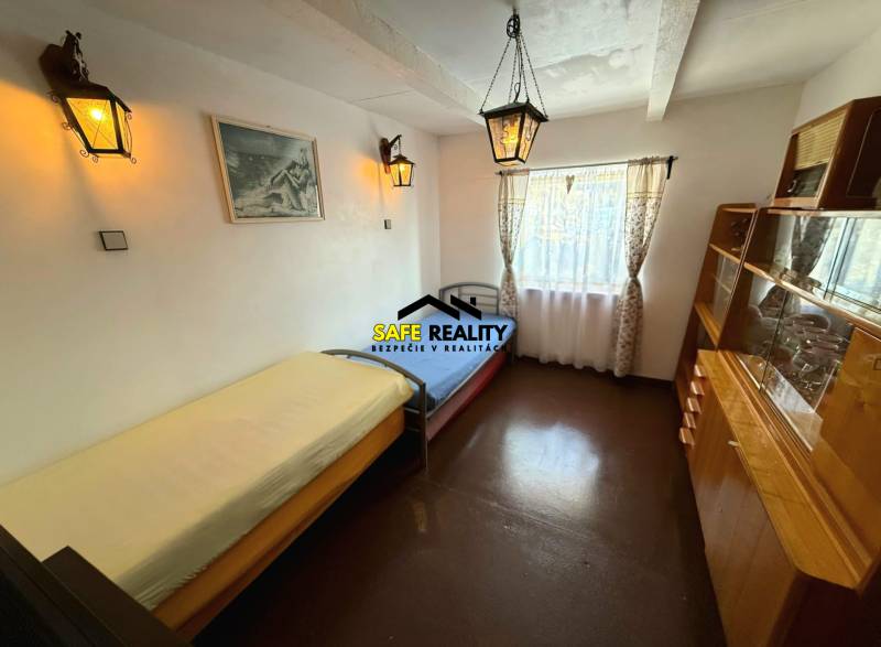 A room in a cottage with simple furniture and a large window, floor with wooden decor.