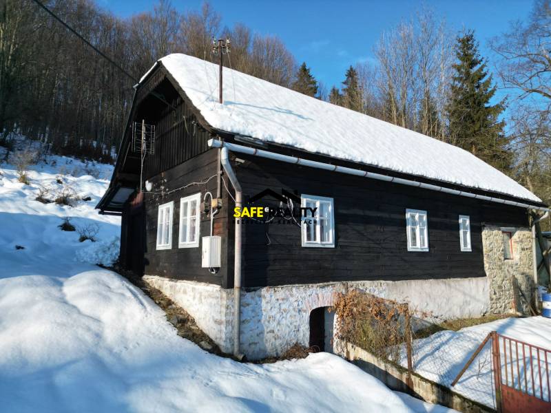 A cottage in Veľké Rovné surrounded by winter nature, snow-covered roof, wooden exterior.