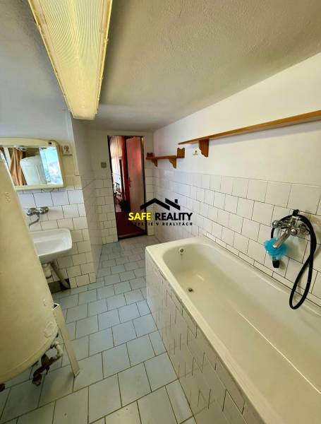 Bathroom in a cabin with white tiles and a bathtub, minimalist arrangement.