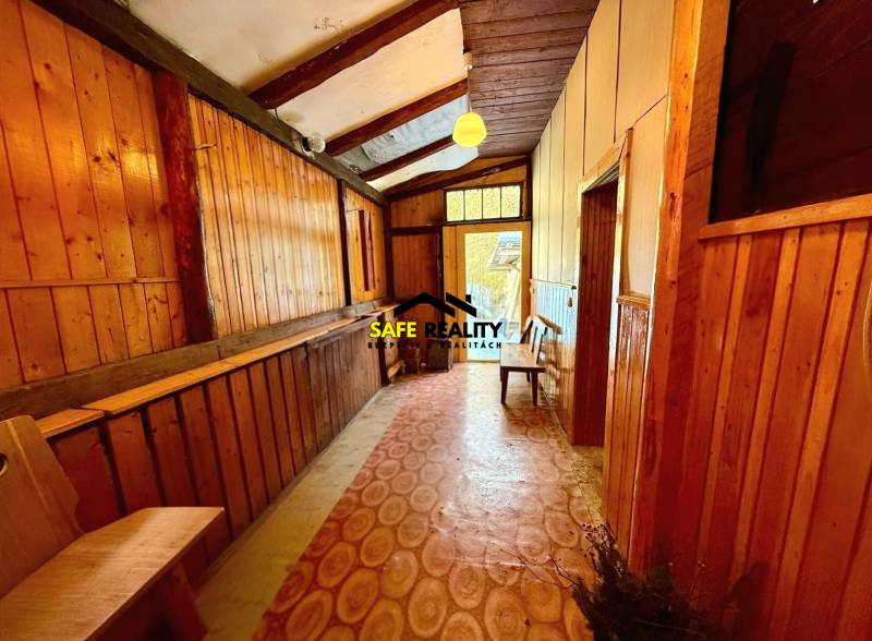 A cabin with wooden paneling and flooring with a wood decor and a bench for seating.