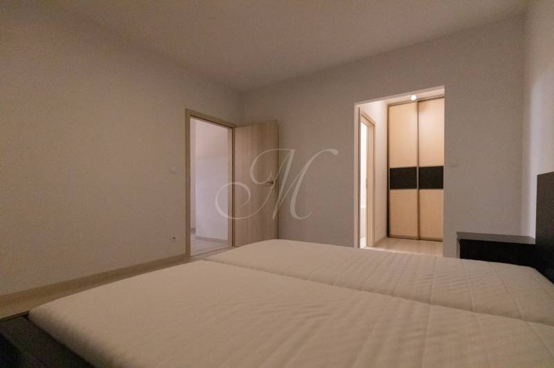 Bedroom with a bed and a wardrobe in a 2-room apartment, floor with a wooden decor.