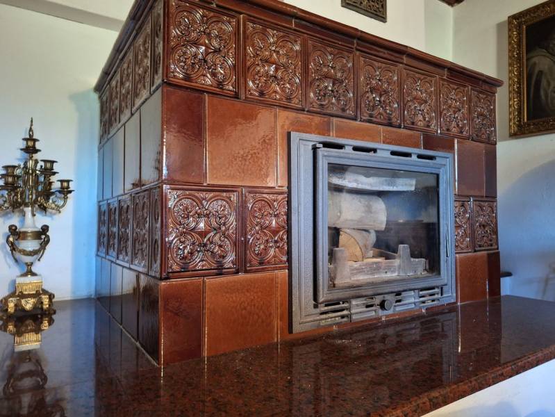A stove with ceramic tiles in a cottage, a decorative candlestick, and antique accessories.