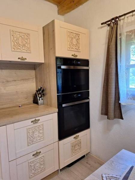 A kitchen in a cabin with carved cabinets, black appliances, and wooden decor.