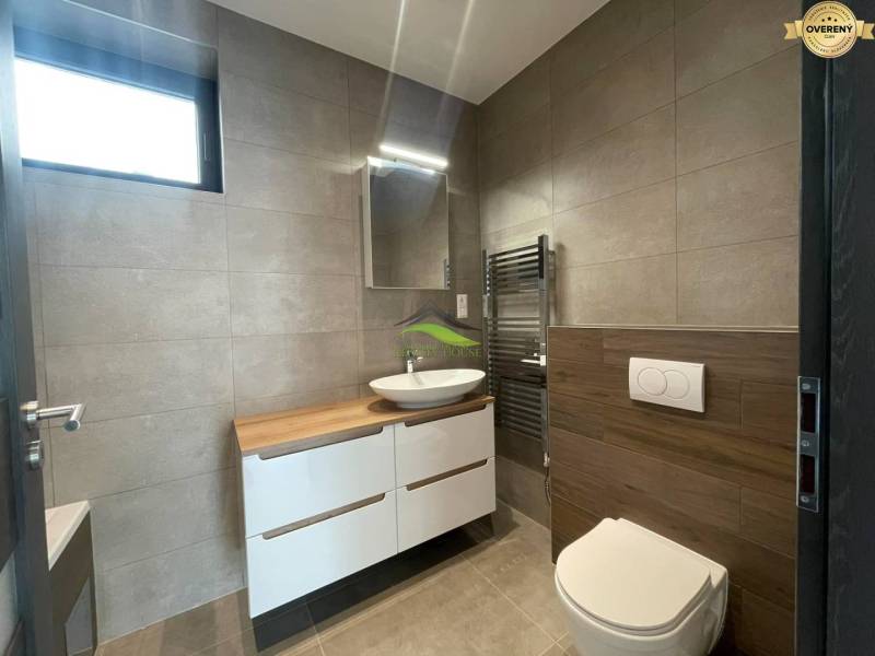 A bathroom in a family house with a sink, a cabinet, and a floor with a wooden decor.