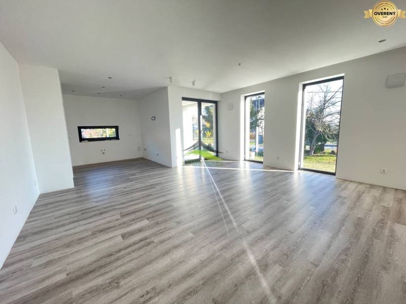 A spacious interior of a family house with a wooden decor floor and large windows.
