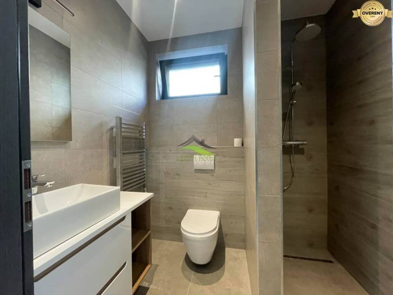 Bathroom in a family house with a sink, toilet, and shower, floor with wooden decor.