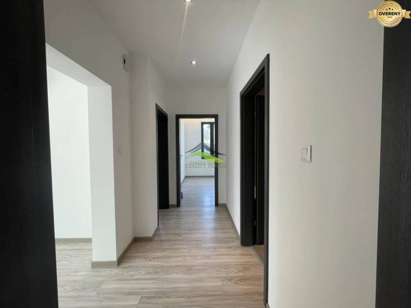 A hallway in a family house with a wooden decor floor and white walls.