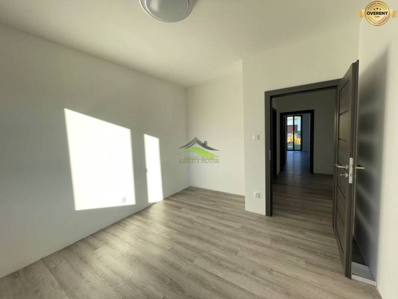 A room with a wooden decor floor in a family house. Light shines through the window.