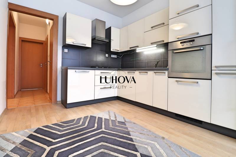 A kitchen unit with black tiles and a floor with a wooden decor in a 3-room apartment.