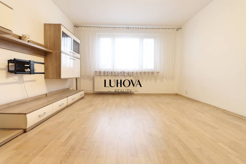 Living room in a three-room apartment with furniture and flooring featuring a wood design.