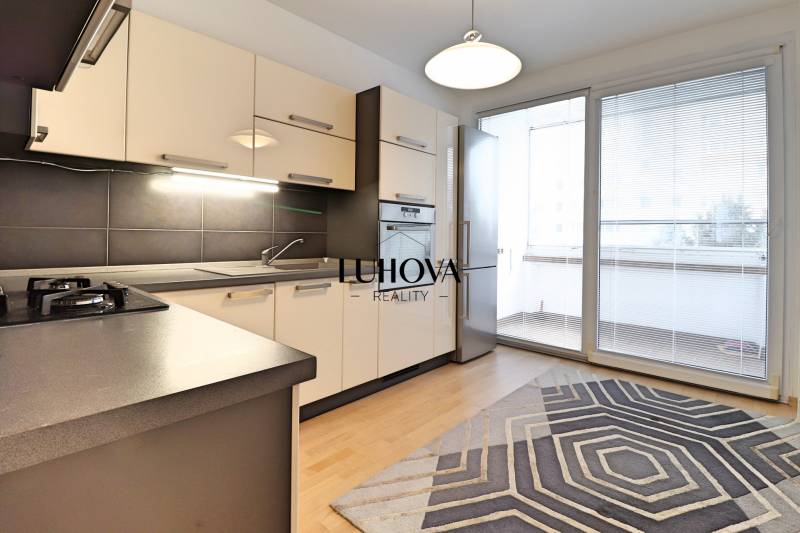 A kitchen in a 3-room apartment with a wooden decor floor and spacious windows.