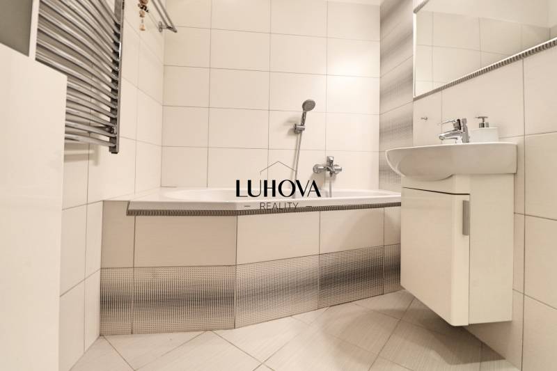 A bathroom with white tiles and a bathtub in a 3-room apartment.